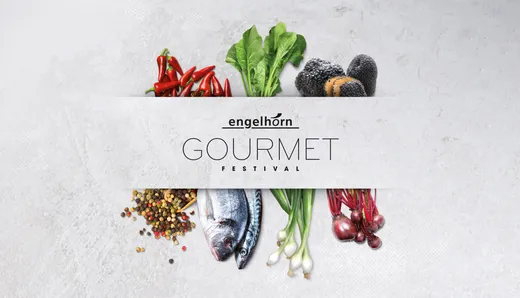 Ein Werbebild für das Engelhorn Gourmet Festival, auf dem frische Zutaten wie Chilischoten, Blattgemüse, schwarze Trüffel, Pfefferkörner, ein Fisch, Frühlingszwiebeln und rote Zwiebeln vor einem hellen Hintergrund zu sehen sind.