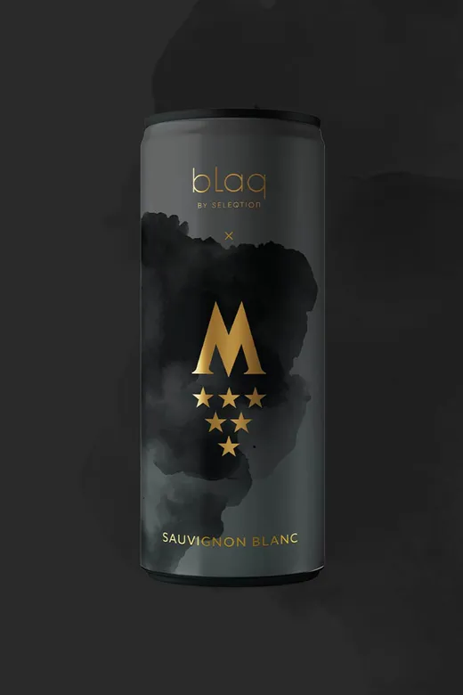 Eine elegante schwarze Dose „blaq by Seleqtion“ Sauvignon Blanc, verziert mit einem goldenen Buchstaben „M“, unter dem sich sechs goldene Sterne befinden, sowie dunklen, abstrakten Wolkenmotiven auf schwarzem Hintergrund.
