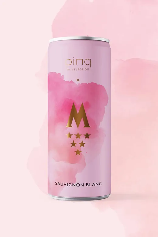 Eine rosafarbene Dose mit Sauvignon-Blanc-Wein, verziert mit goldener Schrift und einem goldenen Motiv, bestehend aus einem großen „M“ und sechs goldenen Sternen auf einem aquarellrosa Hintergrund. Oben steht der Markenname „pinq by Selection“.